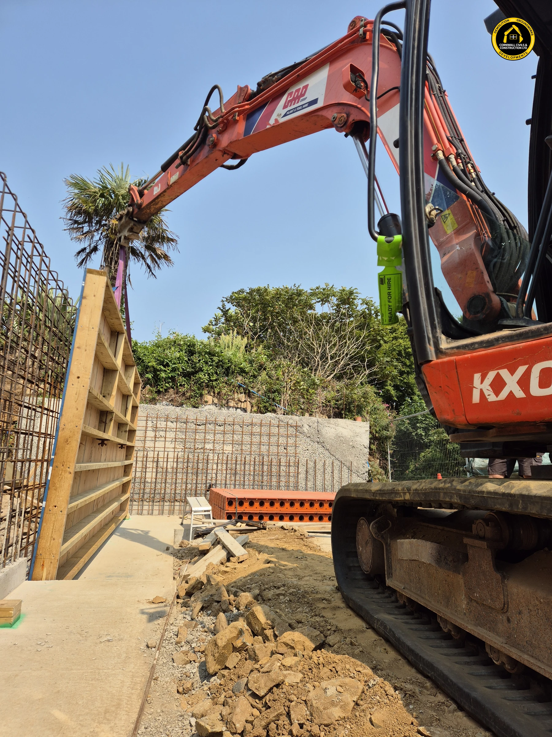 Excavator lifting timber shutter panels into position at Carrick Lodge in St Ives